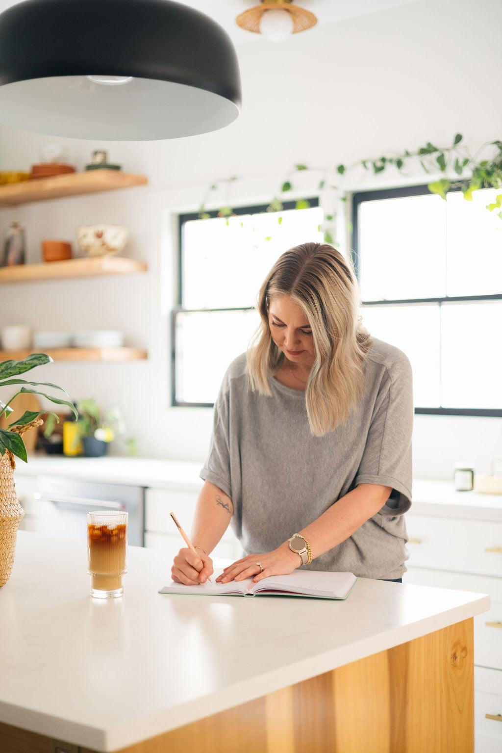 Adult writing a brief morning wellness note over breakfast