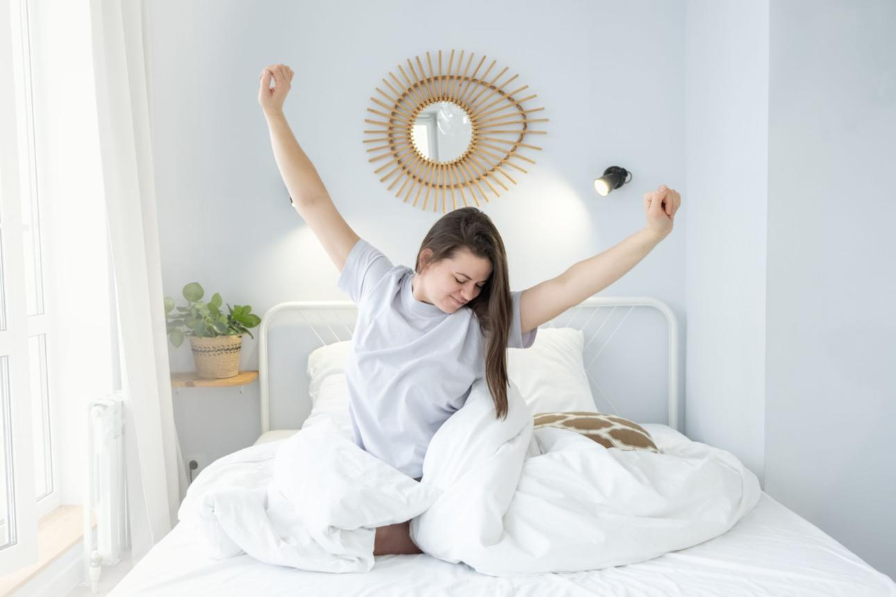 Person waking up in a bright bedroom, stretching